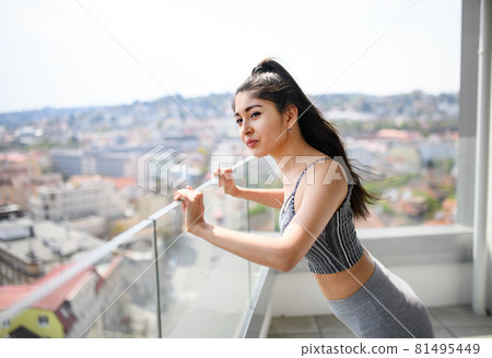 Portrait of young sport woman doing exercise on balcony outdoors in city, stretching. Portrait of young sport woman doing exercise on balcony outdoors in city, stretching. 81495449