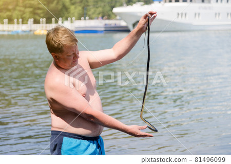 A man caught a poisonous snake while swimming in the water, holds it by the tail A man caught a poisonous snake while swimming in the water, holds it by the tail 81496099