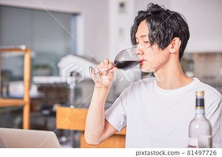 Young man drinking wine at an online drinking party Young man drinking wine at an online drinking party 81497726