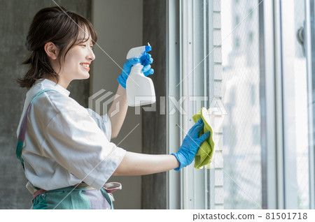 一邊噴灑清潔劑一邊擦窗戶的女人 81501718