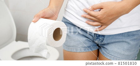 portrait of a woman suffers from diarrhea his stomach painful. ache and problem. hand hold tissue paper roll in front of toilet bowl. constipation in bathroom. Hygiene, health care concept. 81501810