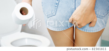 portrait of a woman suffers from diarrhea his stomach painful. ache and problem. hand hold tissue paper roll in front of toilet bowl. constipation in bathroom. Hygiene, health care concept. 81501811