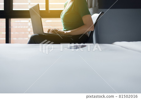 Close up of woman working on laptop while sitting on chair in bedroom with flare light,Happy and enjoying time,Positive thinking Close up of woman working on laptop while sitting on chair in bedroom with flare light,Happy and enjoying time,Positive thinking 81502016