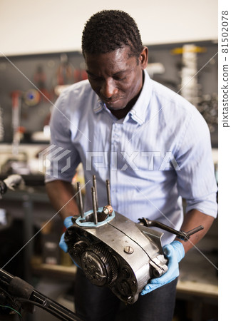 Mechanic installs a repaired engine on a motorcycle 81502078