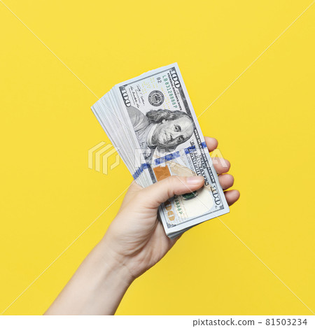 Hand holding a big stack of banknotes isolated on yellow background. Wealth or loan concept 81503234