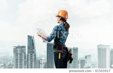 Female engineer in hardhat standing with blueprint Female engineer in hardhat standing with blueprint 81503917