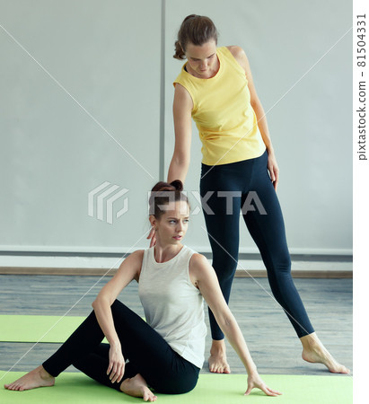 Good shape female Yoga master helps the newcomer student to practice basic gesture and correct to body pose. Concept for learning new skill in class for health and mind 81504331