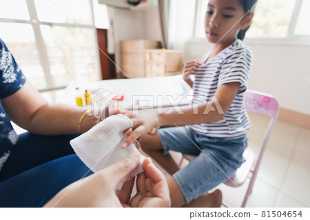 Parent helping her child perform first aid finger injury after she has been an accident. 81504654