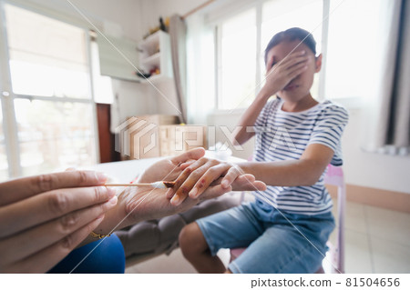 Asian child girl feeling scared while parent helping her perform first aid finger injury after she has been an accident. 81504656