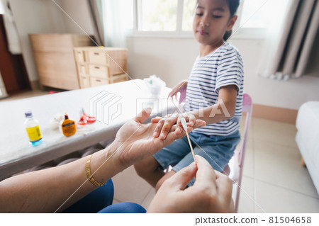 Parent helping her child perform first aid finger injury after she has been an accident. 81504658