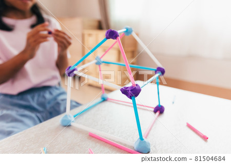 Cute asian child girl playing and creating with playdough and straws. Child concentrated with playdough building a molecule model. Kid and craft with recycle things. 81504684
