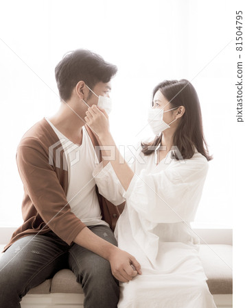 亞洲年輕女性和亞洲年輕男性在家戴外科口罩防止隔離感染新冠肺炎或流感 亞洲年輕女性和亞洲年輕男性在家戴外科口罩防止隔離感染新冠肺炎或流感 81504795