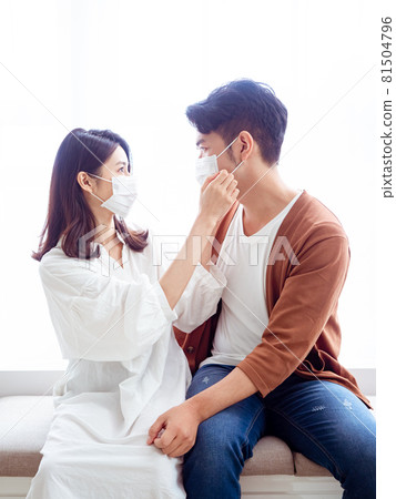 亞洲年輕女性和亞洲年輕男性在家戴外科口罩防止隔離感染新冠肺炎或流感 亞洲年輕女性和亞洲年輕男性在家戴外科口罩防止隔離感染新冠肺炎或流感 81504796