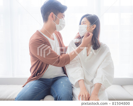 亞洲年輕女性和亞洲年輕男性在家戴外科口罩防止隔離感染新冠肺炎或流感 亞洲年輕女性和亞洲年輕男性在家戴外科口罩防止隔離感染新冠肺炎或流感 81504800