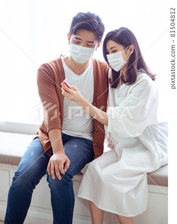 亞洲年輕女性和亞洲年輕男性在家戴外科口罩防止隔離感染新冠肺炎或流感 亞洲年輕女性和亞洲年輕男性在家戴外科口罩防止隔離感染新冠肺炎或流感 81504812