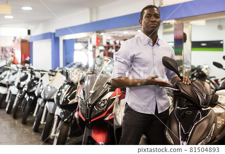 Afro american man is shopping and choosing new motobike in moto store 81504893