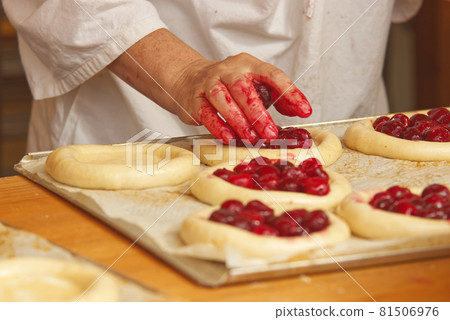 The woman in the picture is making filled fruit pies. Hands filling pie yeast dough with strawberries. Work in the bakery. The woman in the picture is making filled fruit pies. Hands filling pie yeast dough with strawberries. Work in the bakery. 81506976