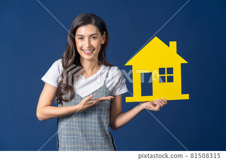 Happy young smiling Asian woman holding and Presenting yellow color house mockup paper on blue color background, thinking for investment, sales and insurance, building and property concept Happy young smiling Asian woman holding and Presenting yellow color house mockup paper on blue color background, thinking for investment, sales and insurance, building and property concept 81508315