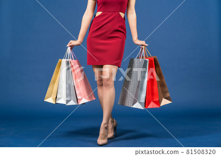 Closeup up Legs of Happy young Asian woman carrying multi color shopping bags on blue color background, summer fashion, black friday and consumerism concept, 81508320