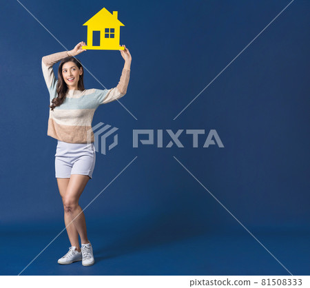 Happy young smiling Asian woman holding and showing yellow color house mockup paper on blue color background, thinking for investment, sales and insurance, building and property concept Happy young smiling Asian woman holding and showing yellow color house mockup paper on blue color background, thinking for investment, sales and insurance, building and property concept 81508333