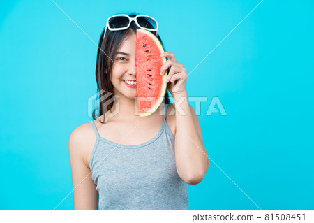 Attractive Asian young woman wearing summer vest and holding the Piece slide of watermelon on isolated blue color background, Sexy mouth bite, copy space and studio, fashion travel and tourist concept Attractive Asian young woman wearing summer vest and holding the Piece slide of watermelon on isolated blue color background, Sexy mouth bite, copy space and studio, fashion travel and tourist concept 81508451