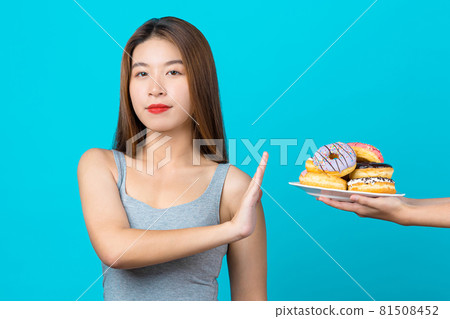 Attractive Asian young woman doing no action with donuts on isolated blue color background, weight loss and avoid junk food for dieting and Healthy concept, copy space and studio Attractive Asian young woman doing no action with donuts on isolated blue color background, weight loss and avoid junk food for dieting and Healthy concept, copy space and studio 81508452