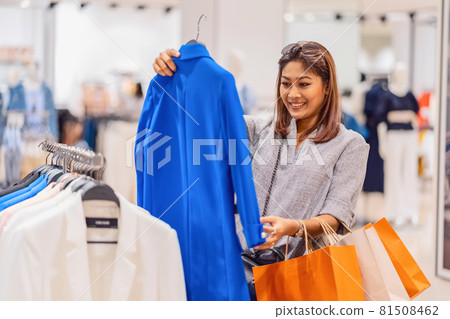 Happy Asian woman choosing clothes in glass store shop with happy action at department center, shopping and shopaholic, lifestyle fashion and leisure, sales and black friday concept Happy Asian woman choosing clothes in glass store shop with happy action at department center, shopping and shopaholic, lifestyle fashion and leisure, sales and black friday concept 81508462