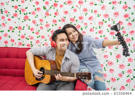 Asian Vlogger of married couple playing the music and taking video and stream live to attendee via mobile phone by social media channel, lovers and valentine, vlog and influencer freelance concept 81508464