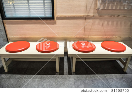 Do NOT SIT SOCIAL DISTANCING Text on the waiting chair in front of restaurant or coffee shop in department store Do NOT SIT SOCIAL DISTANCING Text on the waiting chair in front of restaurant or coffee shop in department store 81508700