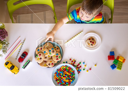 Funny male brothers eat cookies with round multi-colored sweets m&m and drink milk. 81509022