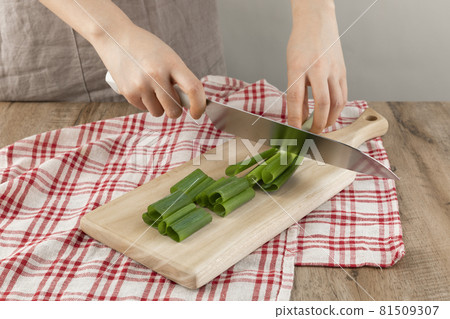cutting green onion with a knife on the cutting board cutting green onion with a knife on the cutting board 81509307