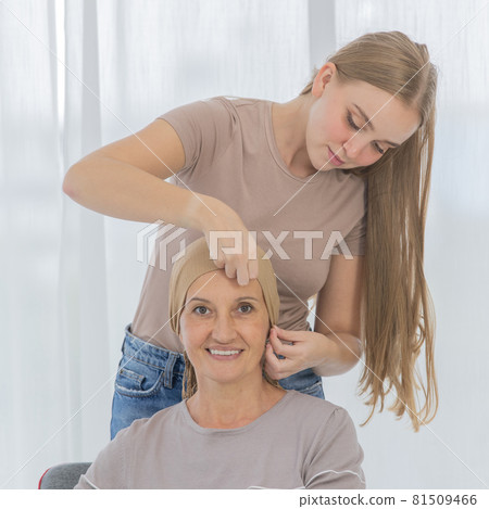 A young and beautiful grateful daughter helping to arrange head scarf to encourage her mother's cancer patient and fortifies her to fight during the chemotherapy. Love and relationship idea A young and beautiful grateful daughter helping to arrange head scarf to encourage her mother's cancer patient and fortifies her to fight during the chemotherapy. Love and relationship idea 81509466