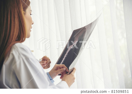 Two asian women doctors discuss meeting doctor's office medical clinic looking x-ray film consulting patient disease. Asian medical lab young women talking together discussing healthcare teamwork Two asian women doctors discuss meeting doctor's office medical clinic looking x-ray film consulting patient disease. Asian medical lab young women talking together discussing healthcare teamwork 81509851