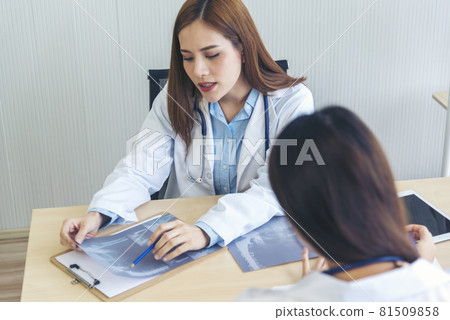 Two asian women doctors discuss meeting doctor's office medical clinic looking x-ray film consulting patient disease. Asian medical lab young women talking together discussing healthcare teamwork Two asian women doctors discuss meeting doctor's office medical clinic looking x-ray film consulting patient disease. Asian medical lab young women talking together discussing healthcare teamwork 81509858