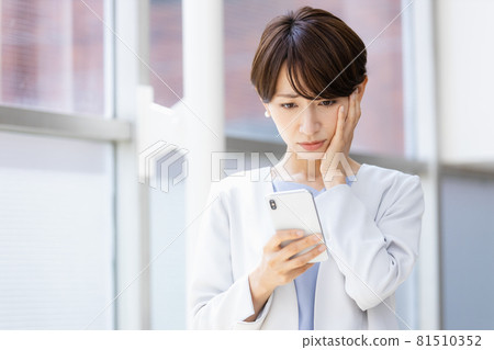 A woman who looks at a smartphone in her hand and shows a negative expression A woman who looks at a smartphone in her hand and shows a negative expression 81510352