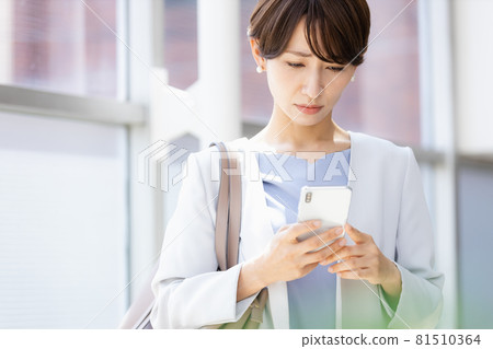A woman who looks at a smartphone in her hand and shows a negative expression 81510364