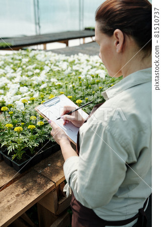 Contemporary farmer making notes on paper while standing by workplace 81510737