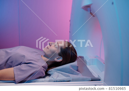 Side view of young woman lying on table of mri scan machine Side view of young woman lying on table of mri scan machine 81510985