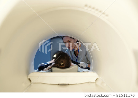 Young assistant looking at little patient before computer tomography examination 81511176