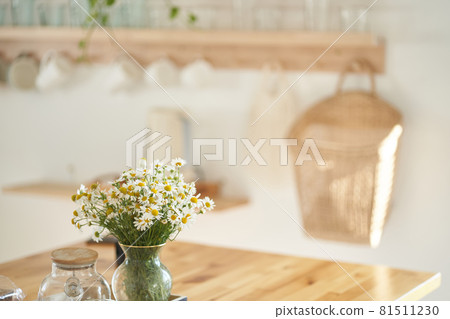 Beautiful white daisy flowers in a glass vase on the kitchen table near the window. Flower arrangement in the home interior, decor. High quality photo Beautiful white daisy flowers in a glass vase on the kitchen table near the window. Flower arrangement in the home interior, decor. High quality photo 81511230