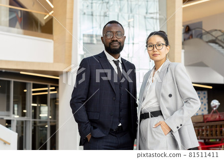 Two young elegant employees in suits standing inside large business center 81511411