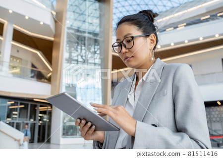 Asian businesswoman with tablet scrolling through online data Asian businesswoman with tablet scrolling through online data 81511416