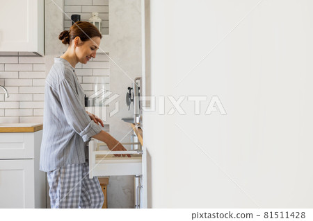 modern housewife tidying up kitchen cupboard during general cleaning or tidying up 81511428