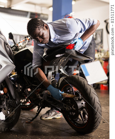 Afro american man working at restoring motorbike in motorcycle workshop 81511771