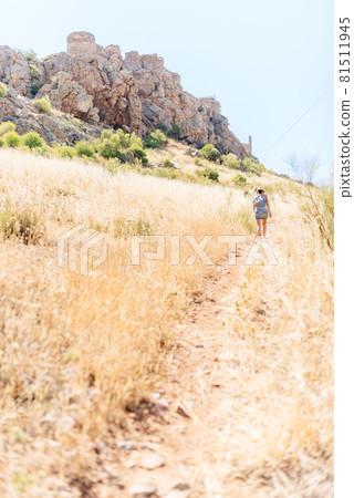 Vertical photo of a woman walking to a hill with a castle. 81511945