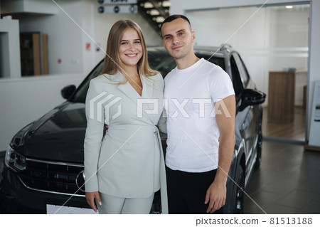 Portrait of beautiful young couple happy after buying new car from car showroom. Woman hus her man and glad Portrait of beautiful young couple happy after buying new car from car showroom. Woman hus her man and glad 81513188