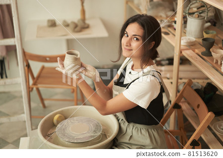 Woman showing handmade clay pot in workshop Woman showing handmade clay pot in workshop 81513620