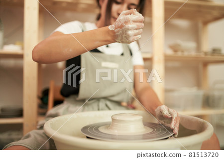 Craftswoman pouring water on wheel Craftswoman pouring water on wheel 81513720