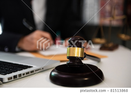 Close up view of auction hammer on the desk in lawyer office and lawyer writing document as courtroom. 81513868