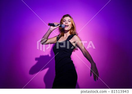 Photo portrait of woman holding microphone in hands isolated on pastel pink colored background Photo portrait of woman holding microphone in hands isolated on pastel pink colored background 81513943